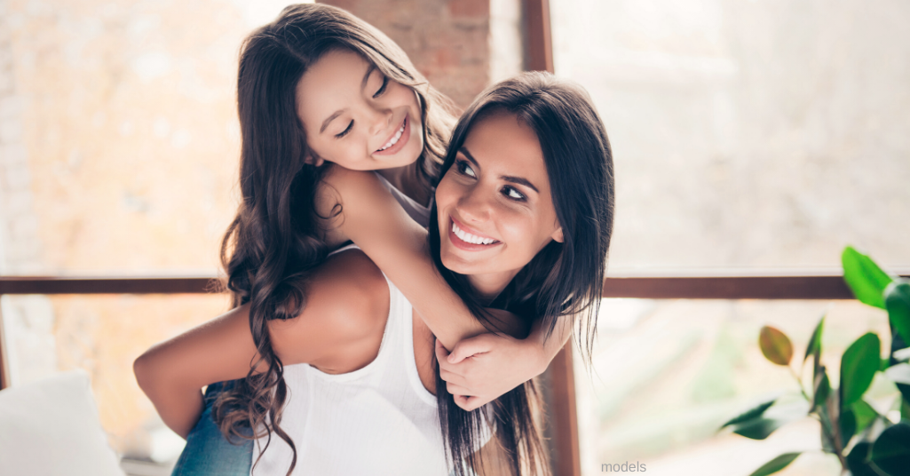 young mother and daughter piggy back (models)